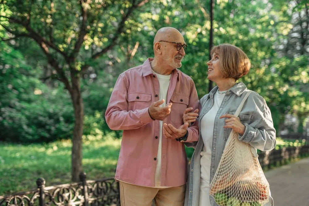 Senior couple walking together in a park enjoying a conversation on a sunny day.