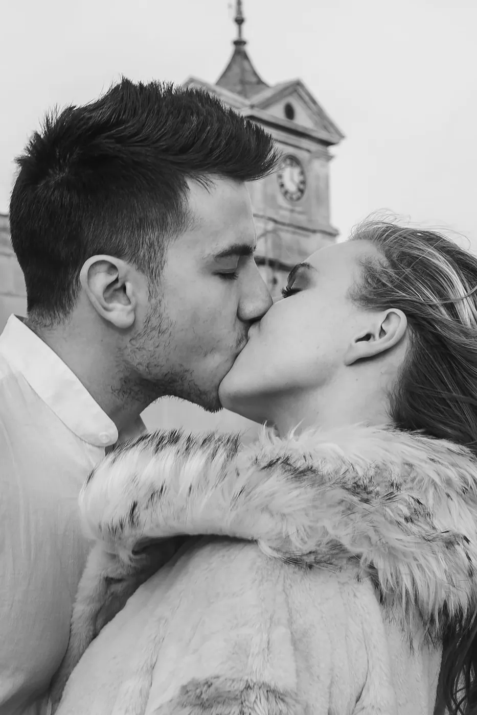 A couple shares a passionate kiss in an intimate black and white street photograph.