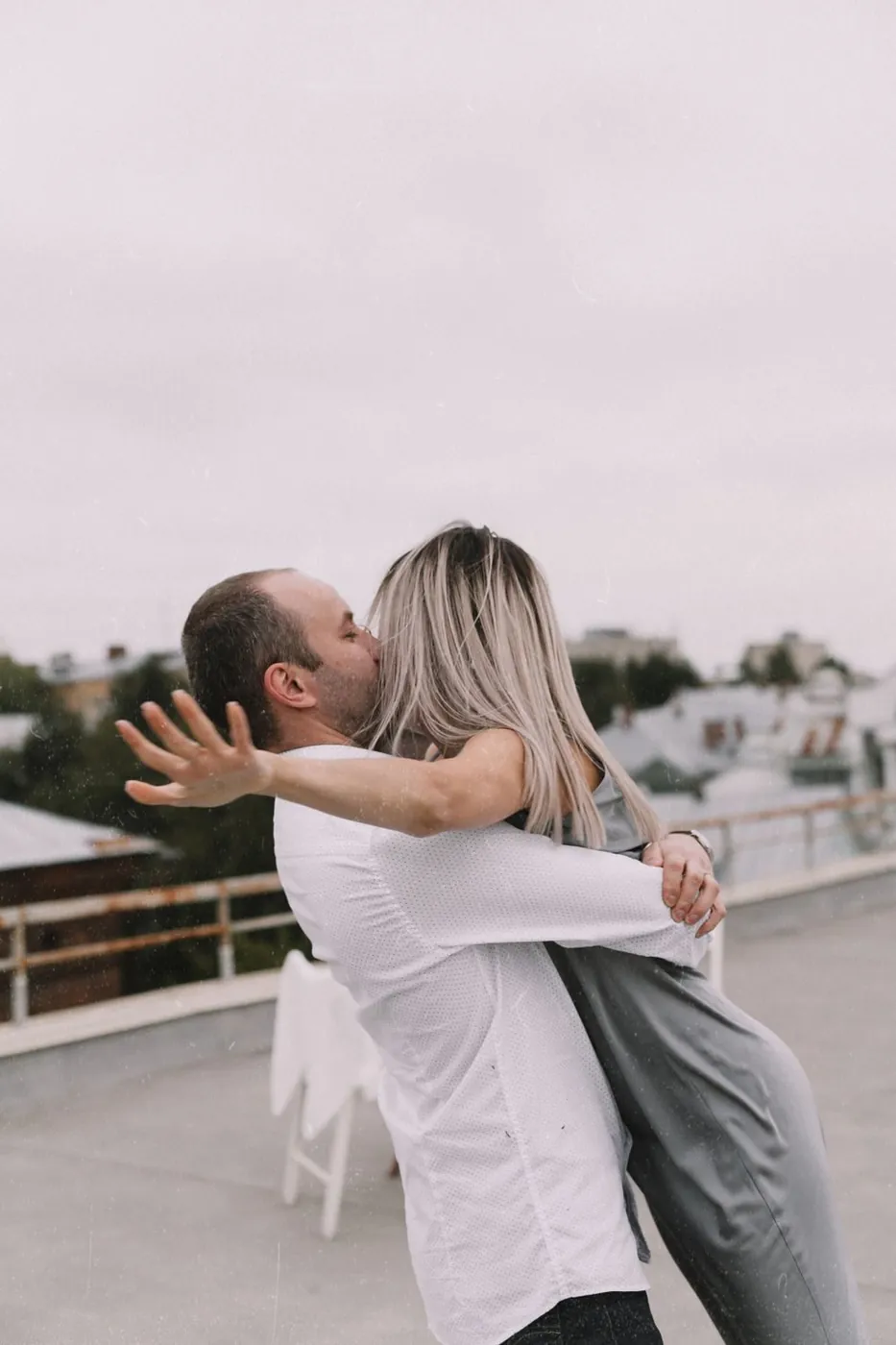 A couple sharing a romantic embrace on an urban rooftop setting.