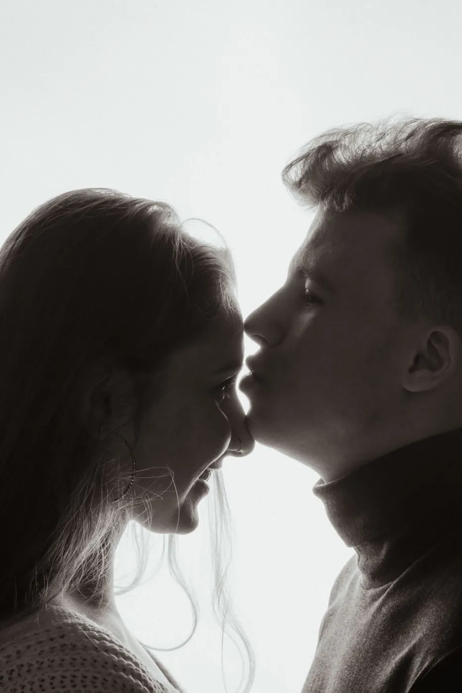 A young couple shares a tender moment in a monochromatic silhouette, exuding love.