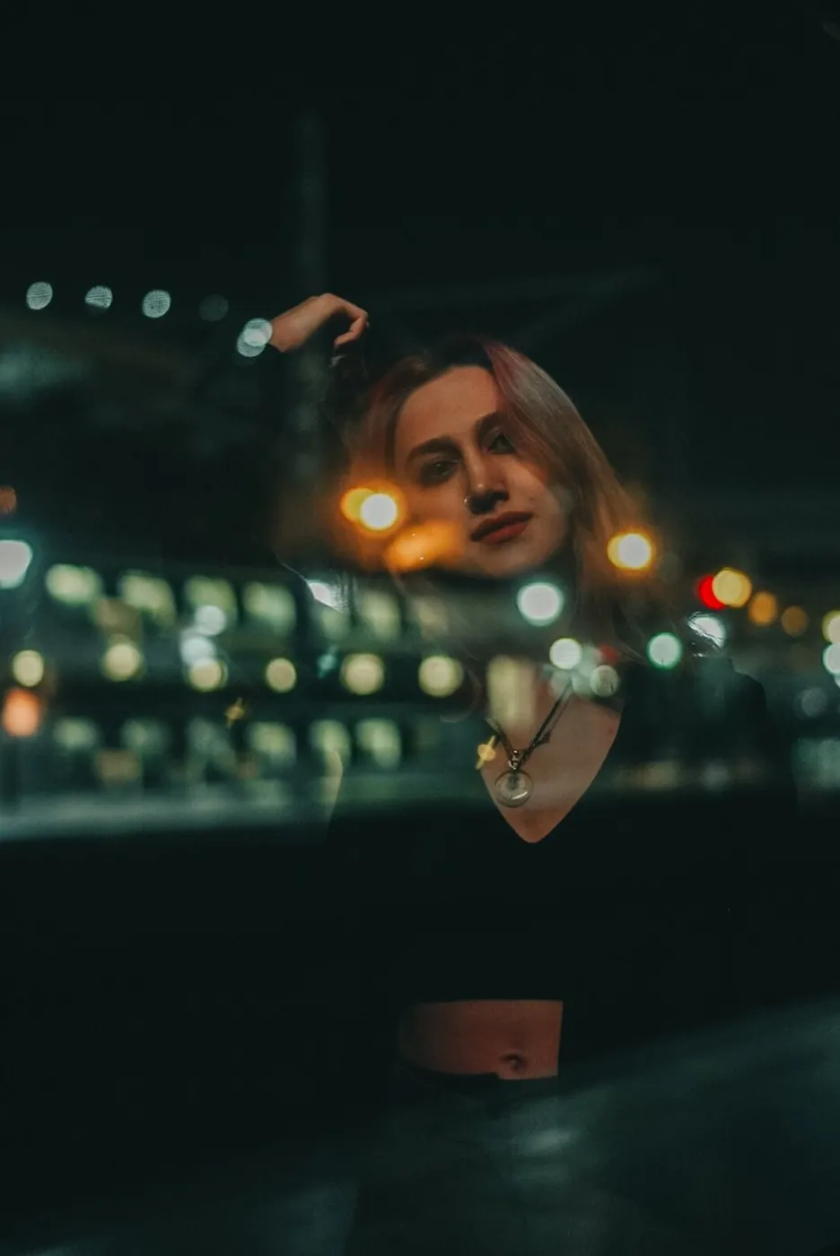 Artistic portrait of a young woman with urban lights at night, emphasizing a modern dark mood.