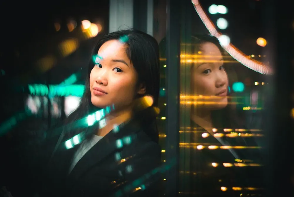 Artistic portrait of an Asian woman with city lights reflection creating a bokeh effect.