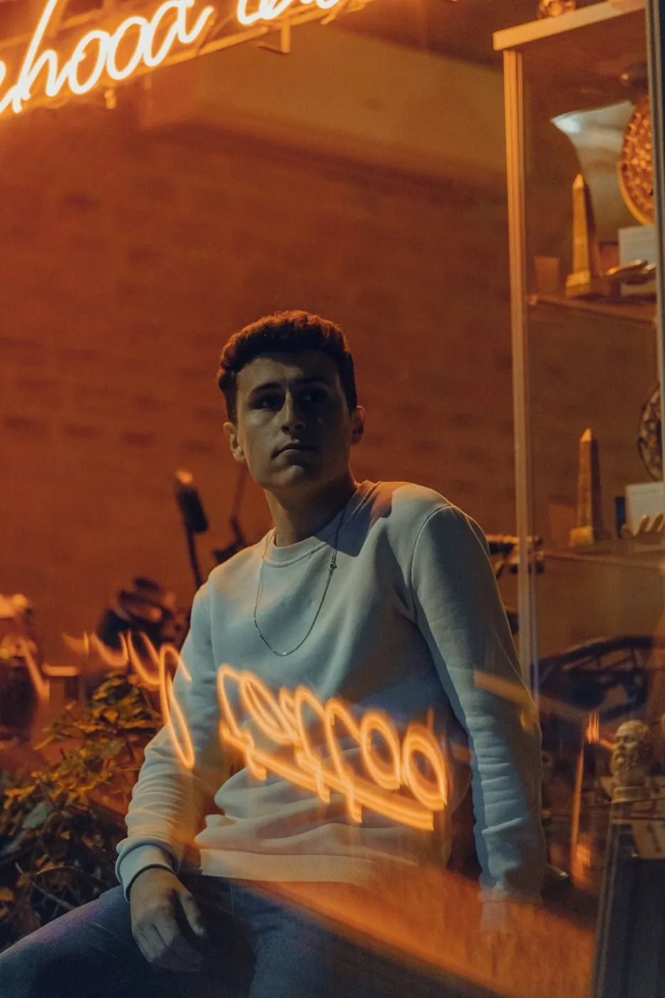 Stylish portrait of a man with neon reflections at night, creating a moody urban vibe.