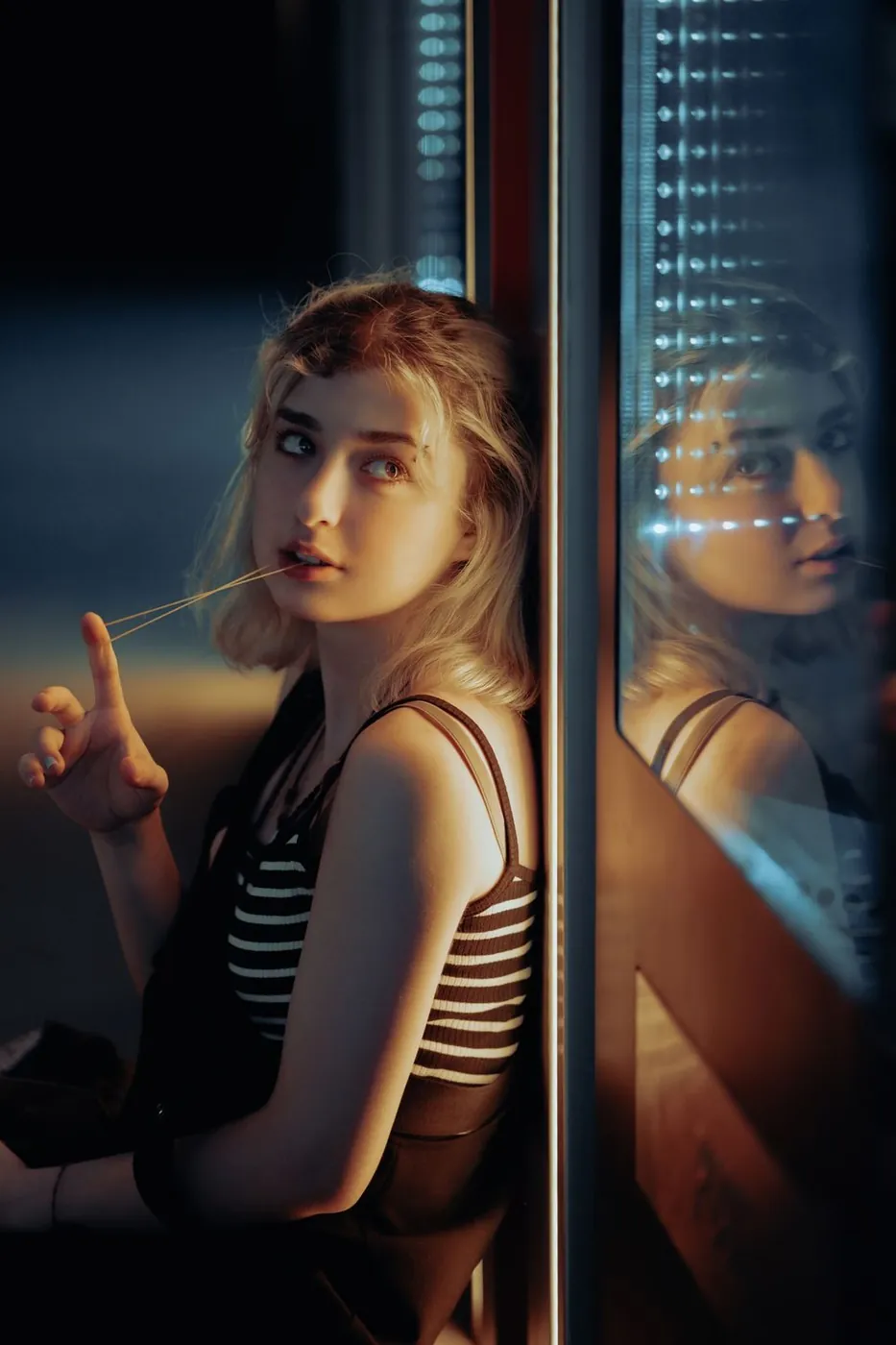 Captivating urban night portrait of a woman with a reflective pose and soft lighting.