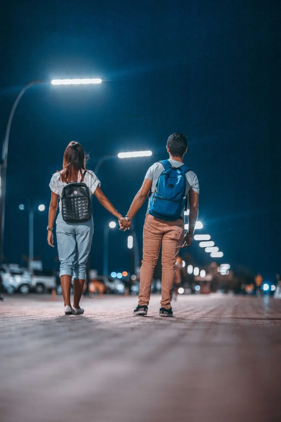 A couple strolls hand-in-hand at night under city lights in Panama City, capturing a romantic urban scene.